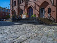 cobblestone driveway surrounded by modern buildings on sunny day with sun reflecting onto the windows