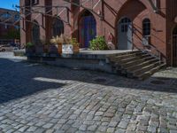 cobblestone driveway surrounded by modern buildings on sunny day with sun reflecting onto the windows