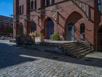 cobblestone driveway surrounded by modern buildings on sunny day with sun reflecting onto the windows