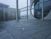 a courtyard with circles on the cement and a bridge behind them, with several light spots on the floor