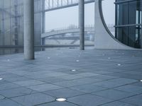 a courtyard with circles on the cement and a bridge behind them, with several light spots on the floor