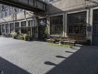 a very pretty courtyard with lots of wooden benches in it and large windows and large windows