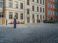 an empty parking lot with plants in the ground and on the side of the building, there is an enclosed area and windows