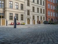 an empty parking lot with plants in the ground and on the side of the building, there is an enclosed area and windows