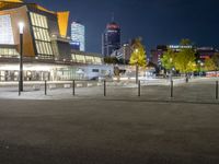 an empty courtyard at night with the city skyline in the background while the street is dark