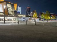 an empty courtyard at night with the city skyline in the background while the street is dark