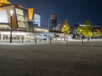 an empty courtyard at night with the city skyline in the background while the street is dark