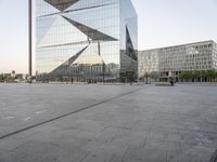 an outdoor area is seen in the background and a large glass building stands with a metal structure near it