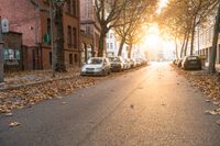 a paved street is lined with parked cars at sunset or dawn or sunset with no other light on