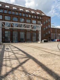 a brick courtyard with a train passing by it and people on it near the building