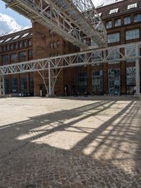 a brick courtyard with a train passing by it and people on it near the building