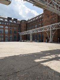 a brick courtyard with a train passing by it and people on it near the building