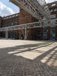 a brick courtyard with a train passing by it and people on it near the building