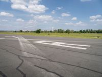 a blue sky with clouds is over an airport runway and some people on it standing near the runway