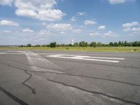 a blue sky with clouds is over an airport runway and some people on it standing near the runway