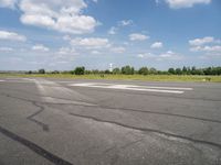 a blue sky with clouds is over an airport runway and some people on it standing near the runway