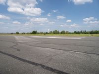 a blue sky with clouds is over an airport runway and some people on it standing near the runway