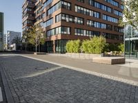 two bikes sit on a street next to a building and trees in the background and one bike is standing on the sidewalk