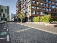 two bikes sit on a street next to a building and trees in the background and one bike is standing on the sidewalk