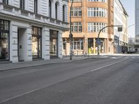 an empty city street in the middle of the day with traffic lights on each corner