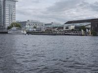 large body of water next to a building near the river with people on it and boats in the water