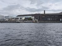 large body of water next to a building near the river with people on it and boats in the water