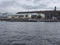 large body of water next to a building near the river with people on it and boats in the water