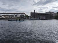 large body of water next to a building near the river with people on it and boats in the water