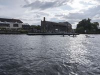 large body of water next to a building near the river with people on it and boats in the water
