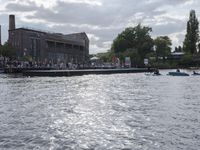 large body of water next to a building near the river with people on it and boats in the water