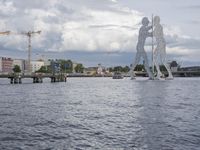 large body of water next to a building near the river with people on it and boats in the water