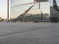 a person riding a scooter on the ground in front of a building that is reflecting other buildings