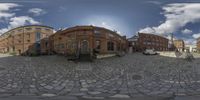 circular photograph showing multiple different buildings in a downtown area with a cobblestone street