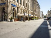 a street is empty of cars and signs along with buildings and people waiting at tables