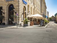 a street is empty of cars and signs along with buildings and people waiting at tables