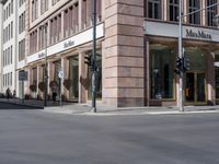 an empty street and building on one side with traffic lights at a corner on the other