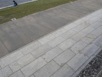 a couple sitting on the edge of a walkway next to a body of water with people in the distance