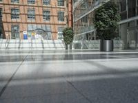 a person is riding a skateboard in a very empty area of the city while a building with glass walls looks on