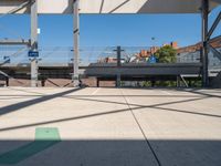 a empty parking lot with buildings in the background and a car parked under an elevated walkway