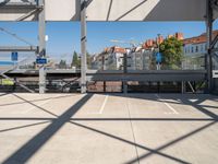 a empty parking lot with buildings in the background and a car parked under an elevated walkway