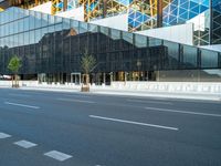 empty street near building and trees in the city on sunny day on street corner with reflections in modern glass