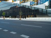 empty street near building and trees in the city on sunny day on street corner with reflections in modern glass