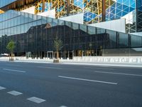 empty street near building and trees in the city on sunny day on street corner with reflections in modern glass