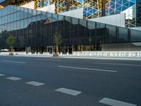 empty street near building and trees in the city on sunny day on street corner with reflections in modern glass