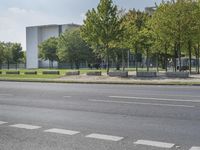 the empty street is next to trees and some buildings in the distances to it