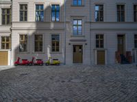 an empty parking lot with plants in the ground and on the side of the building, there is an enclosed area and windows