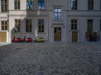 an empty parking lot with plants in the ground and on the side of the building, there is an enclosed area and windows