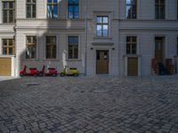 an empty parking lot with plants in the ground and on the side of the building, there is an enclosed area and windows