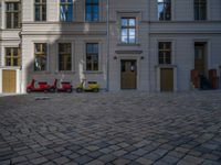 an empty parking lot with plants in the ground and on the side of the building, there is an enclosed area and windows