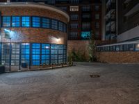 some dark blue windows in an industrial building with no one on the street to the right